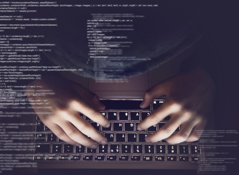 Man's hands typing on a keyboard in the dark
